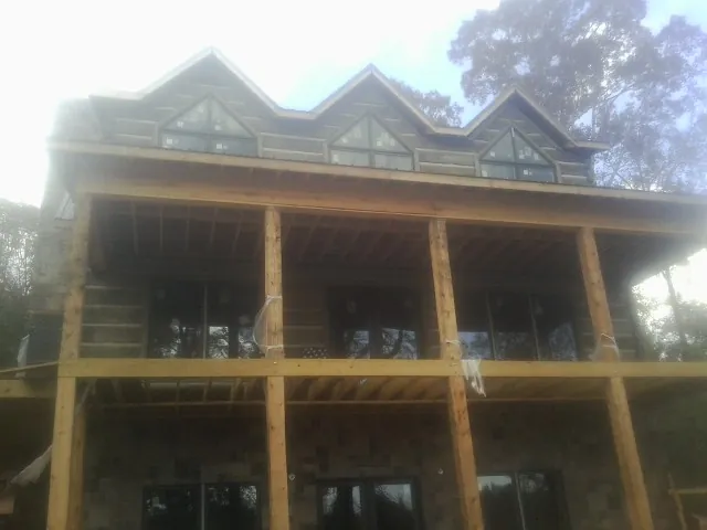 Dormers and porch framing on a large log home under construction — Roof Coating work by our crew in Colon