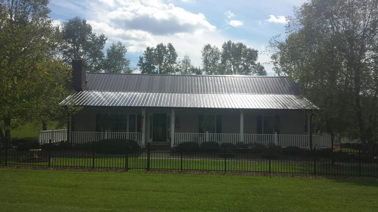 Gray metal roof on a brick ranch with a full width front porch — Gutter Guard Installation work by our crew in Colon