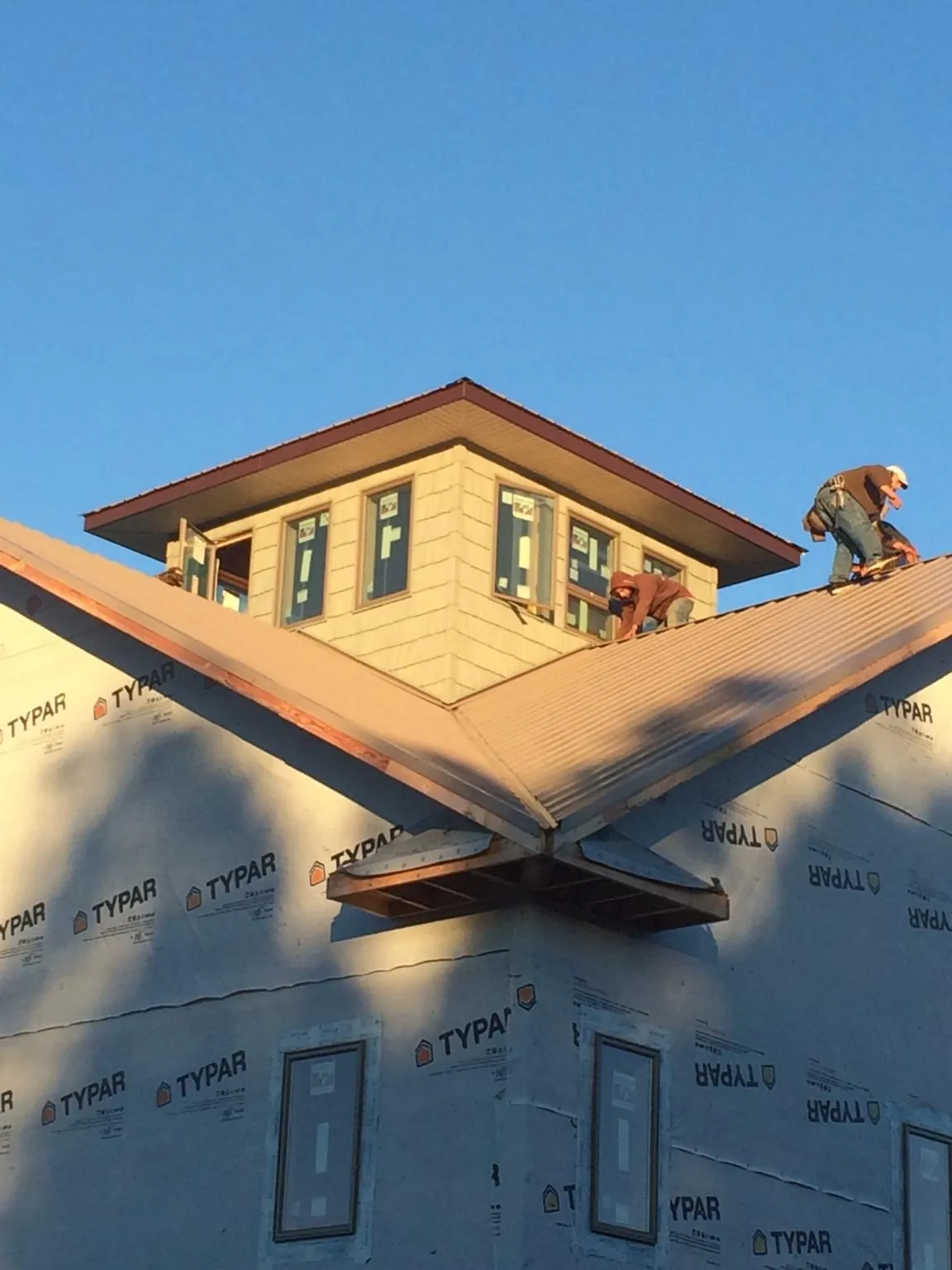 Roofers working around a rooftop cupola on a new metal roof at sunset — Roof Waterproofing in Colon by Roofing Brothers